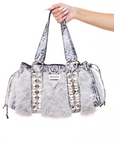 Handbag with faux fur, snakeskin and stud details held by a hand on a white background
