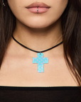Close-up of a person wearing a black choker with a blue polka dot cross pendant.