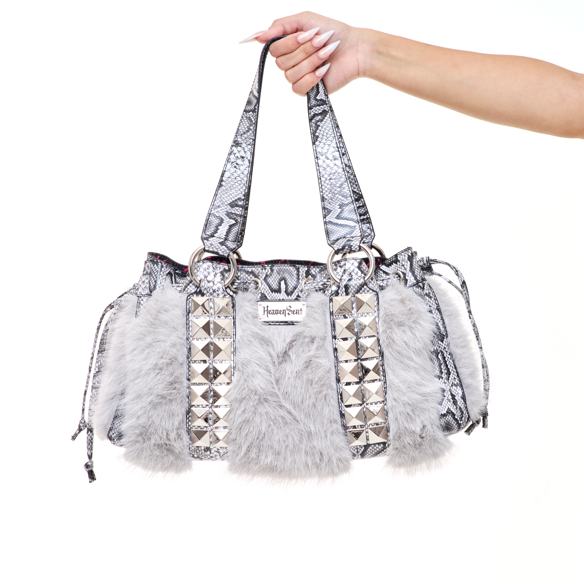 Handbag with faux fur, snakeskin and stud details held by a hand on a white background