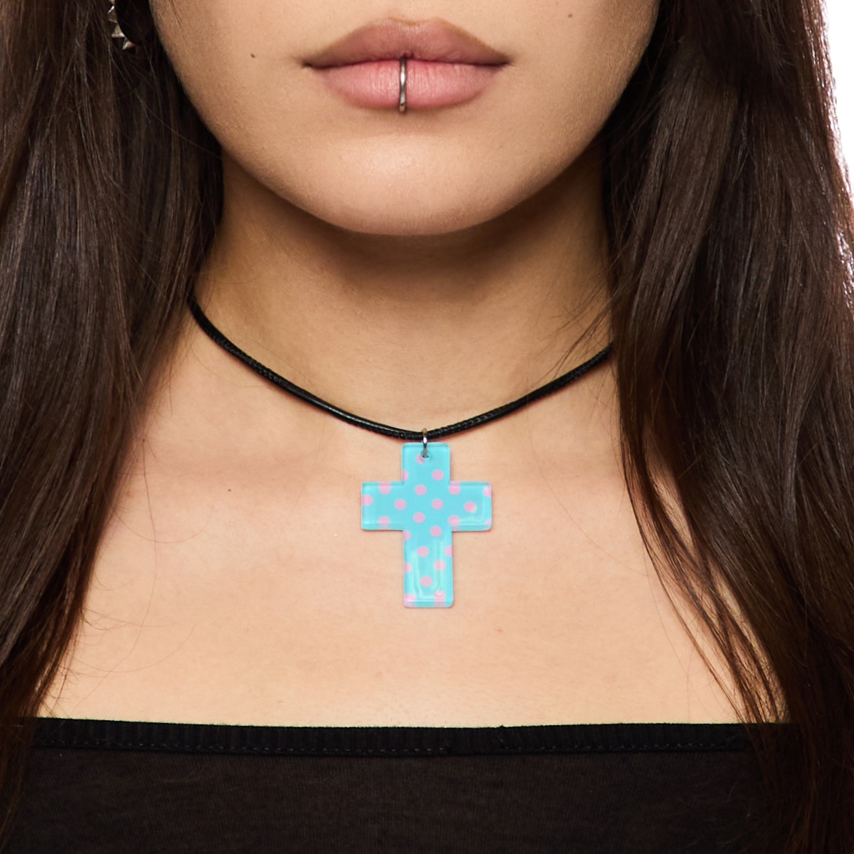 Close-up of a person wearing a black choker with a blue polka dot cross pendant.